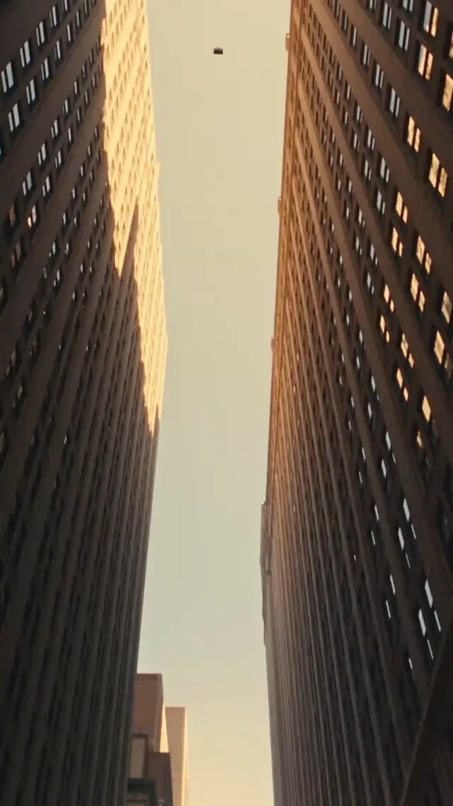 Black leather handbag falls from skyscrapers onto crushed red sedan in golden dust